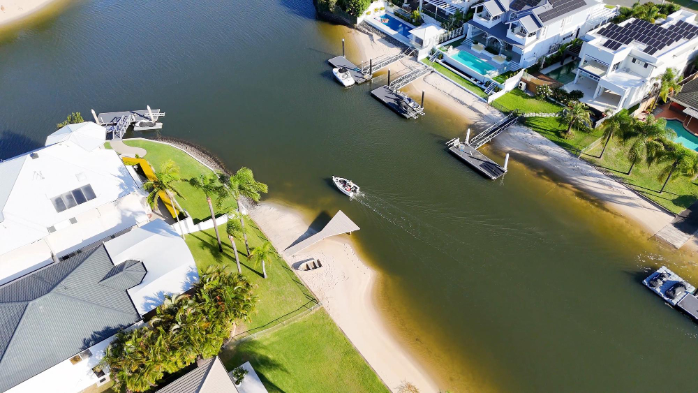 Aerial view of waterfront homes, docks, and boat on canal