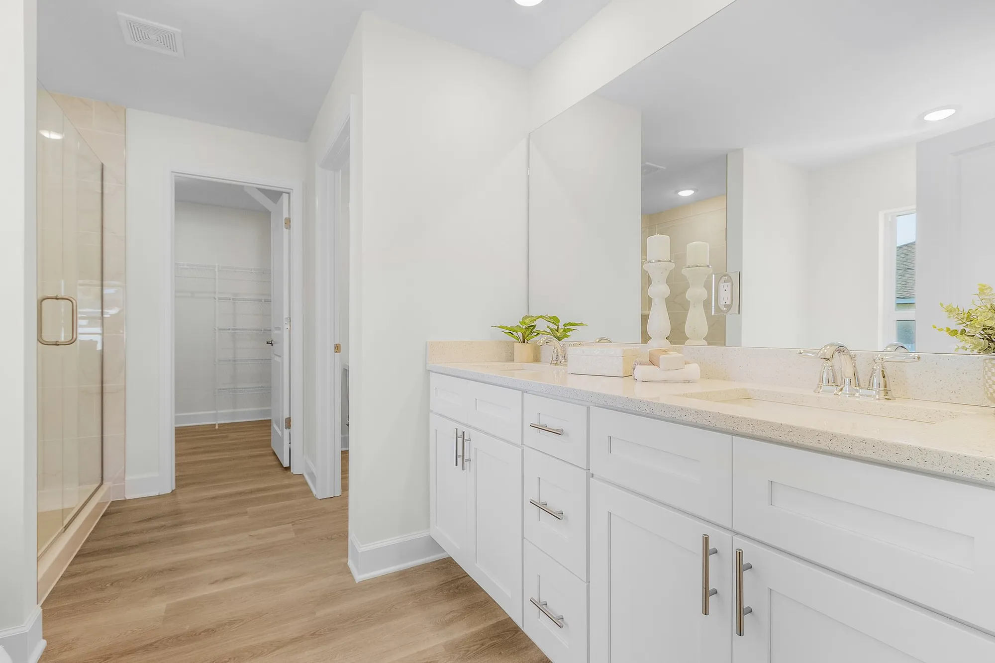 Bright bathroom with white vanity, mirror, and glass shower