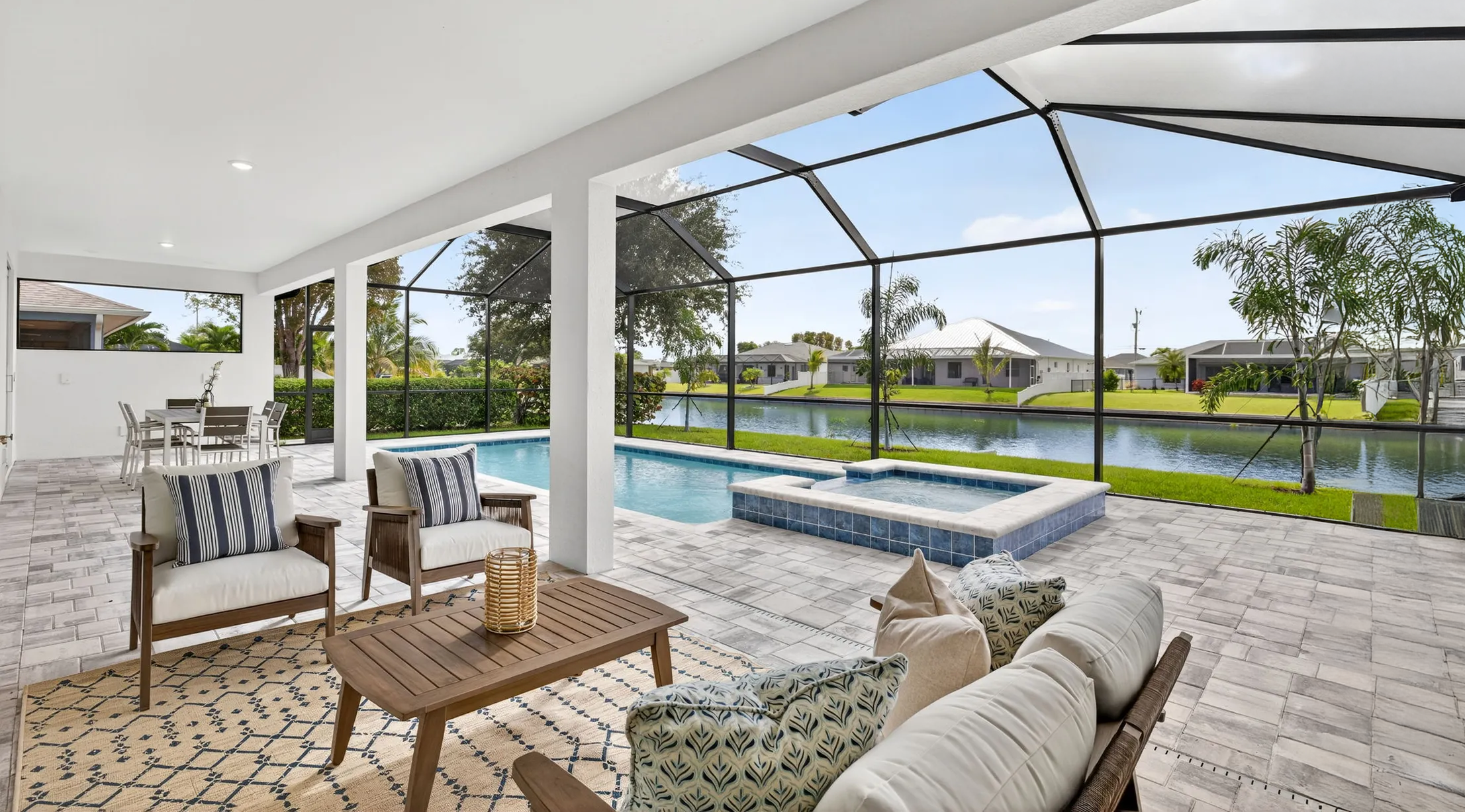 Covered patio seating beside screened pool and spa overlooking lake