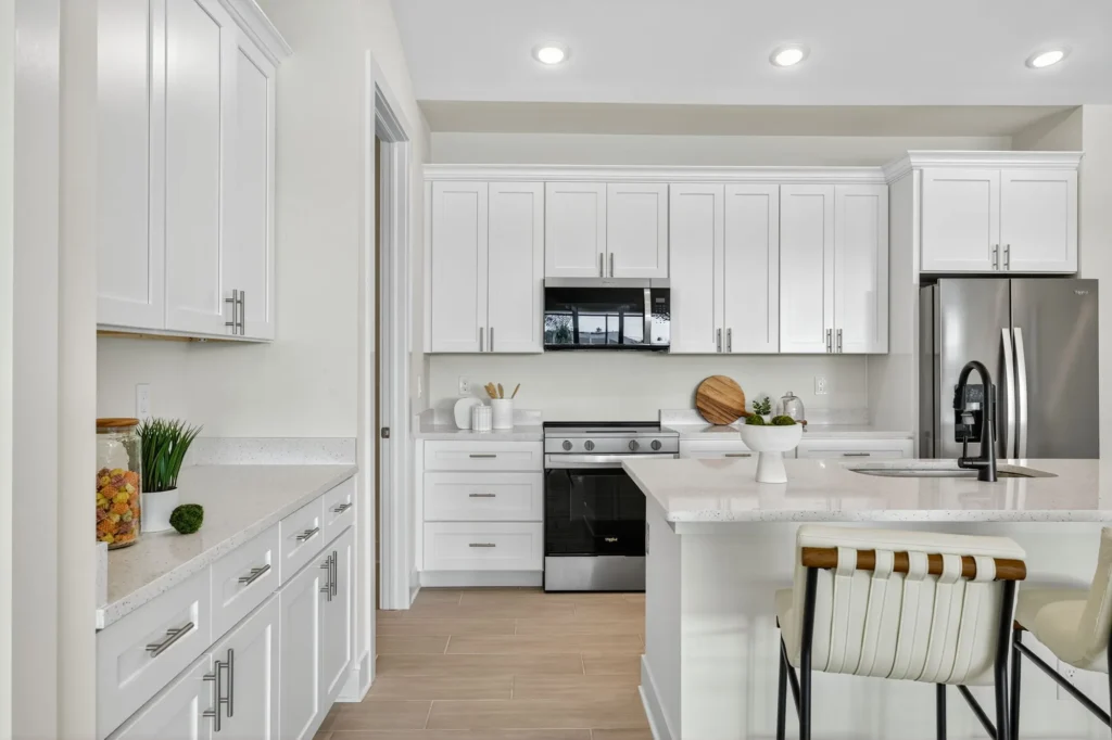 Bright white kitchen with island, stainless appliances, barstools
