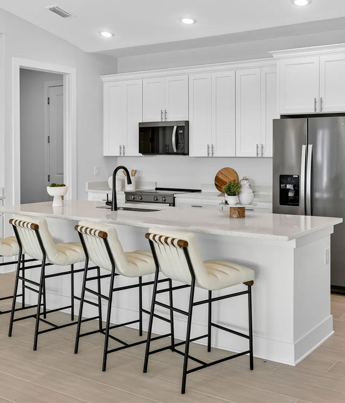 White kitchen island with four bar stools and stainless appliances