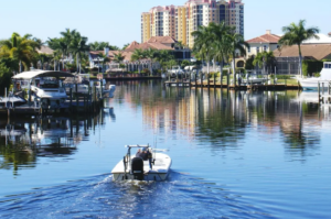 Small boat cruising canal past palm-lined waterfront homes