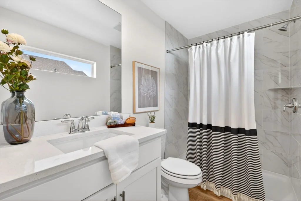 Bright bathroom with vanity sink, toilet, and shower curtain