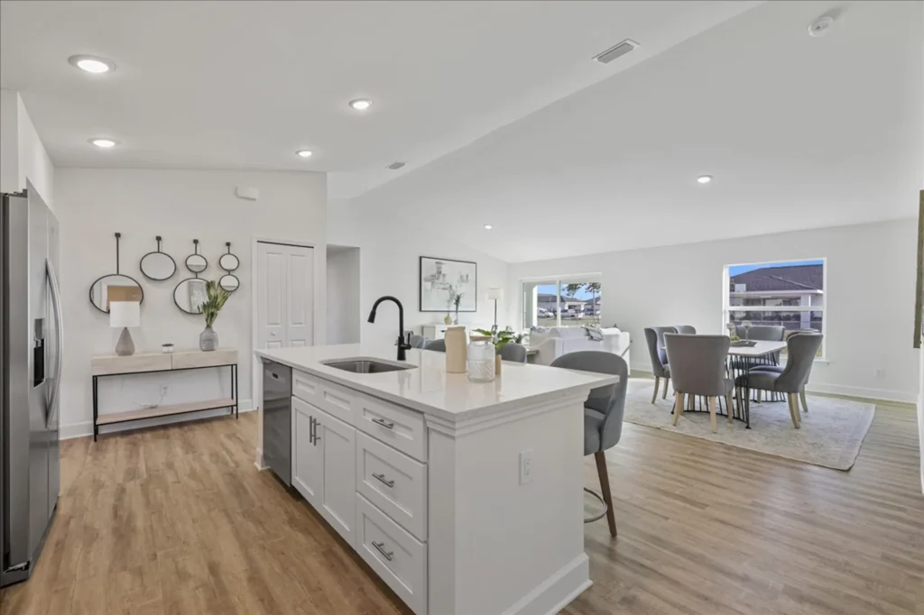Open kitchen with white island flowing into dining area.