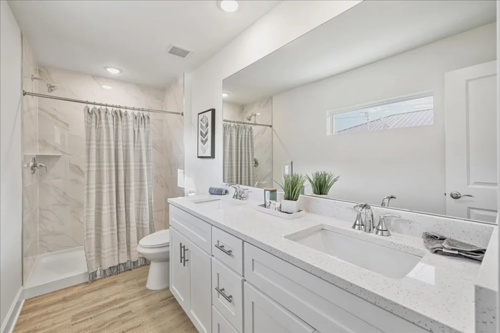 Bright bathroom with double vanity and tiled shower
