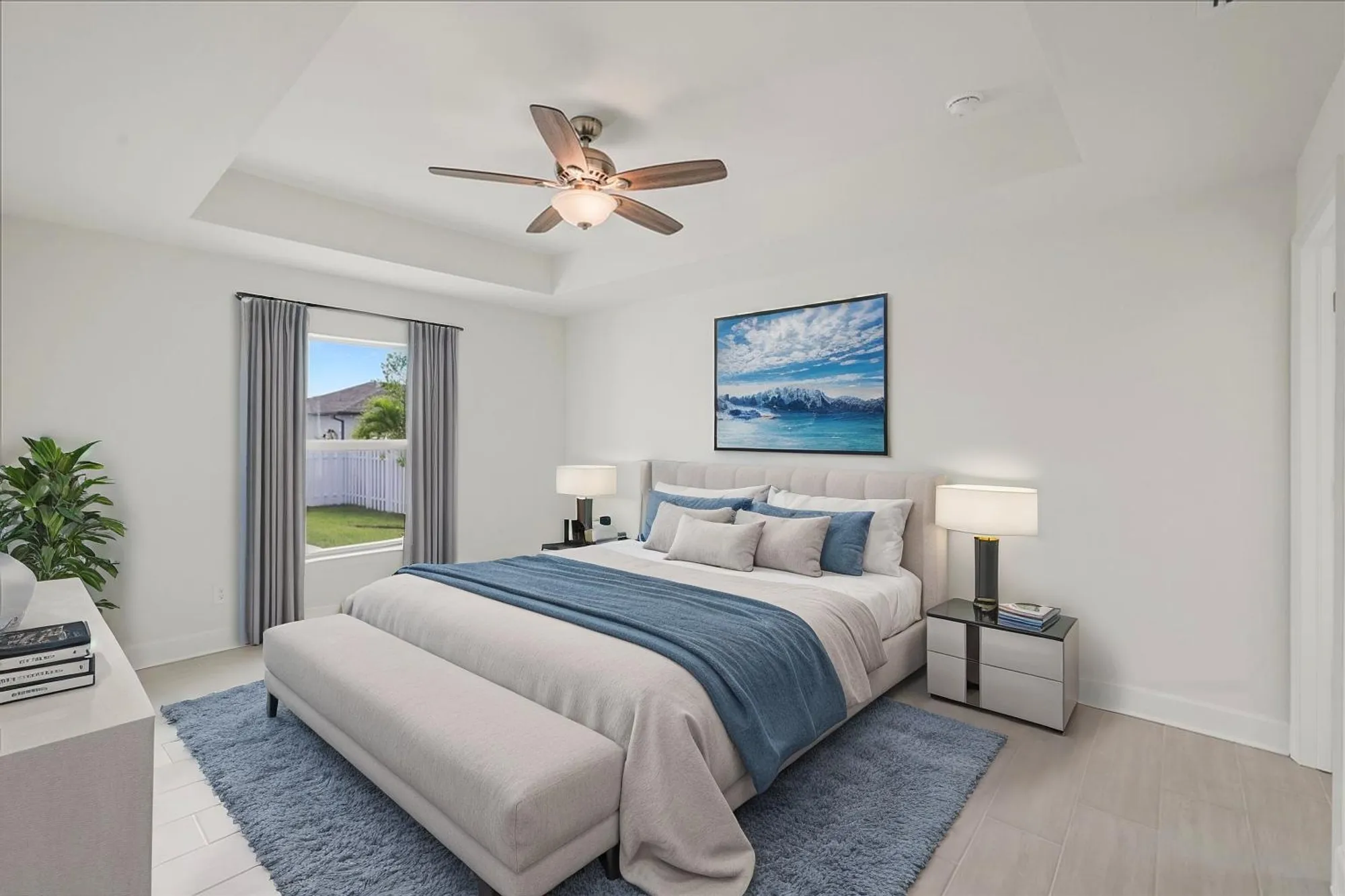 Modern bedroom with blue bedding, ceiling fan, and window
