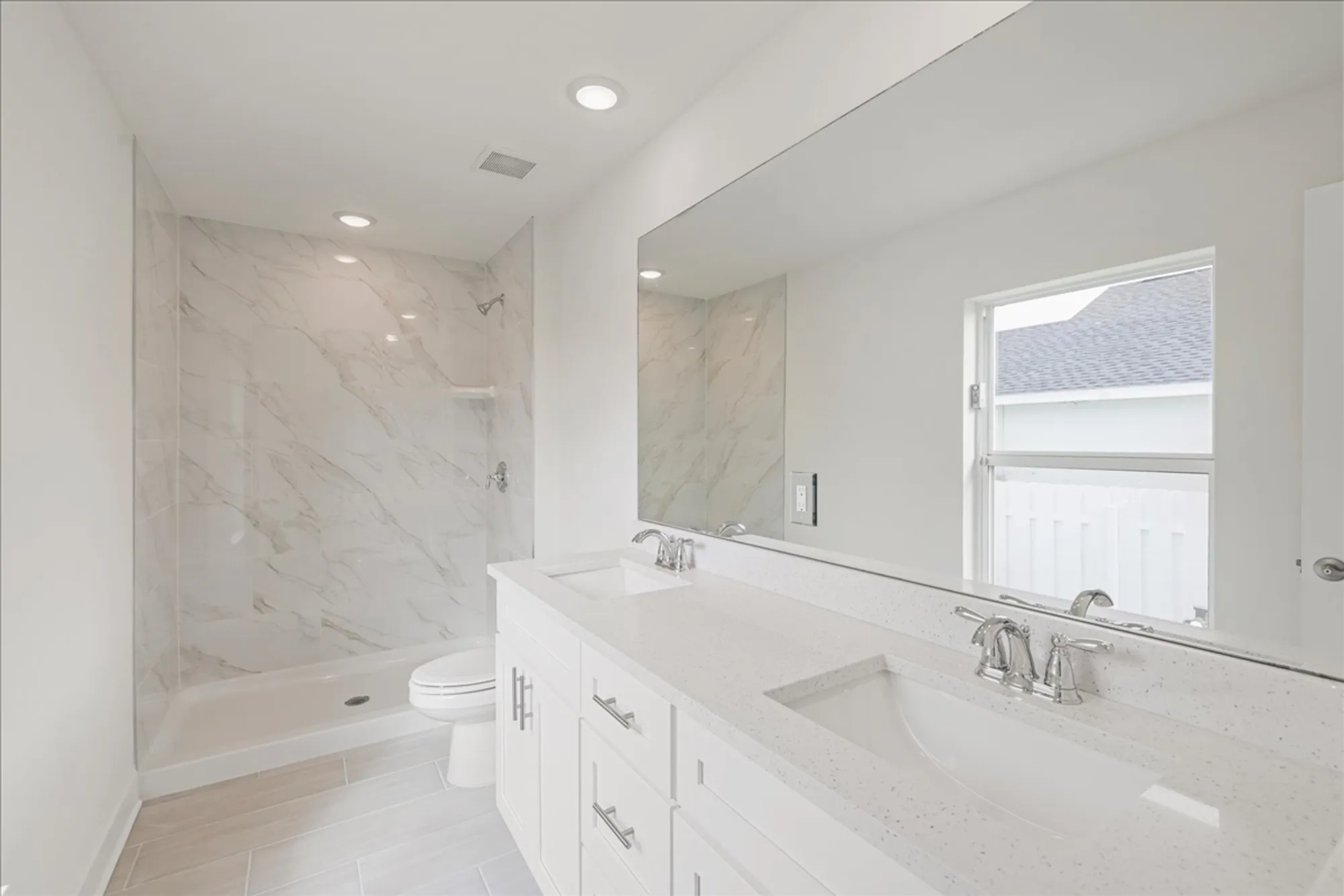 Bright bathroom with double vanity, large mirror, walk-in shower