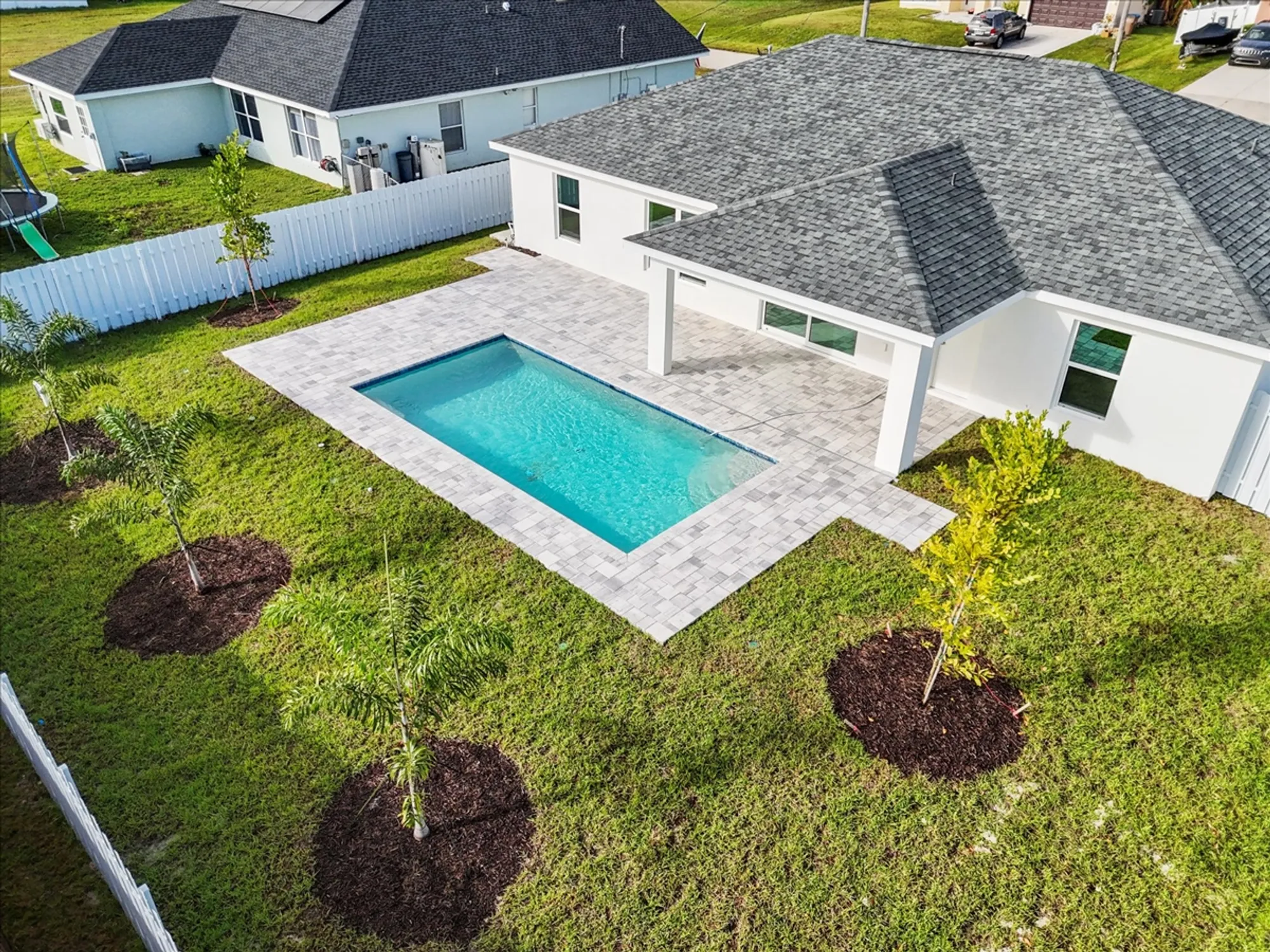Aerial view of backyard pool with paver patio and lawn