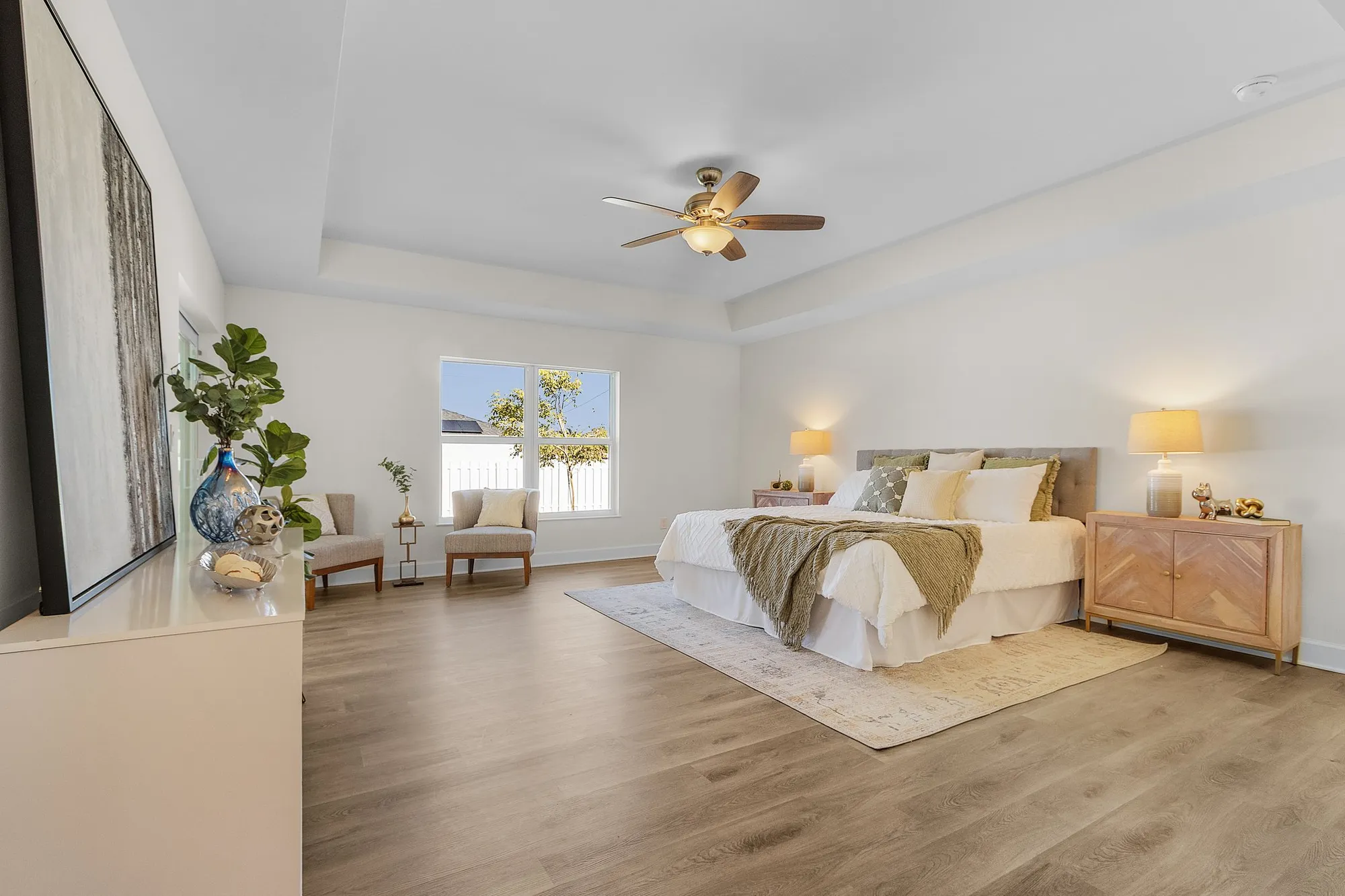 Spacious bedroom with bed, ceiling fan, and seating area