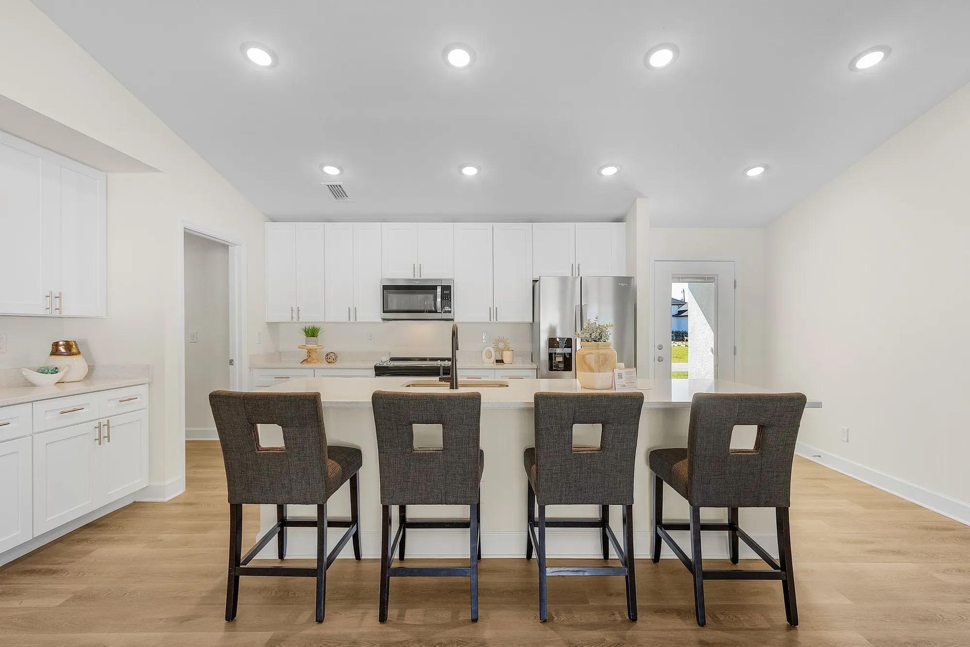 Modern white kitchen with island and four bar stools.