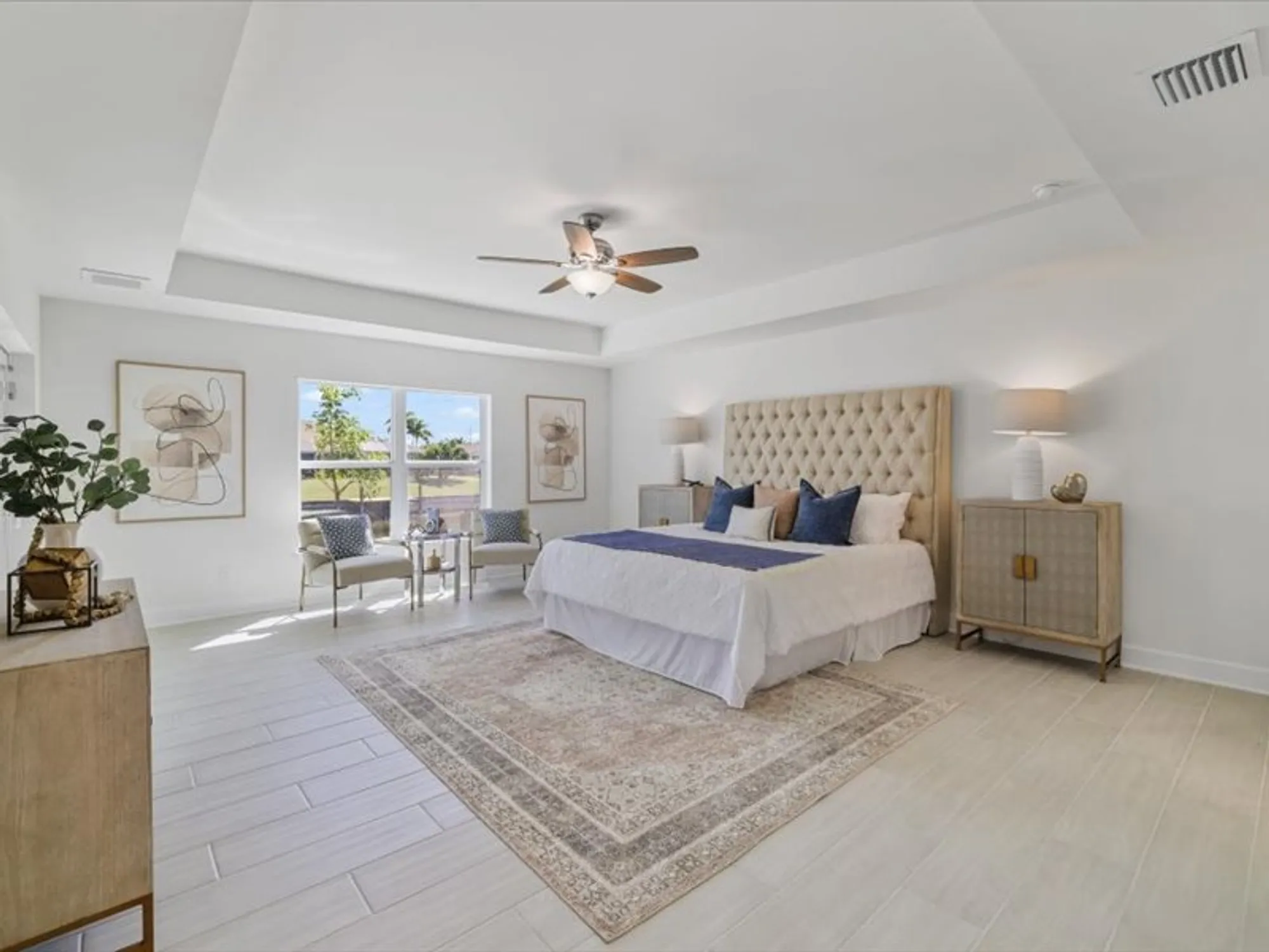 Bright bedroom with upholstered bed, ceiling fan, and window seating