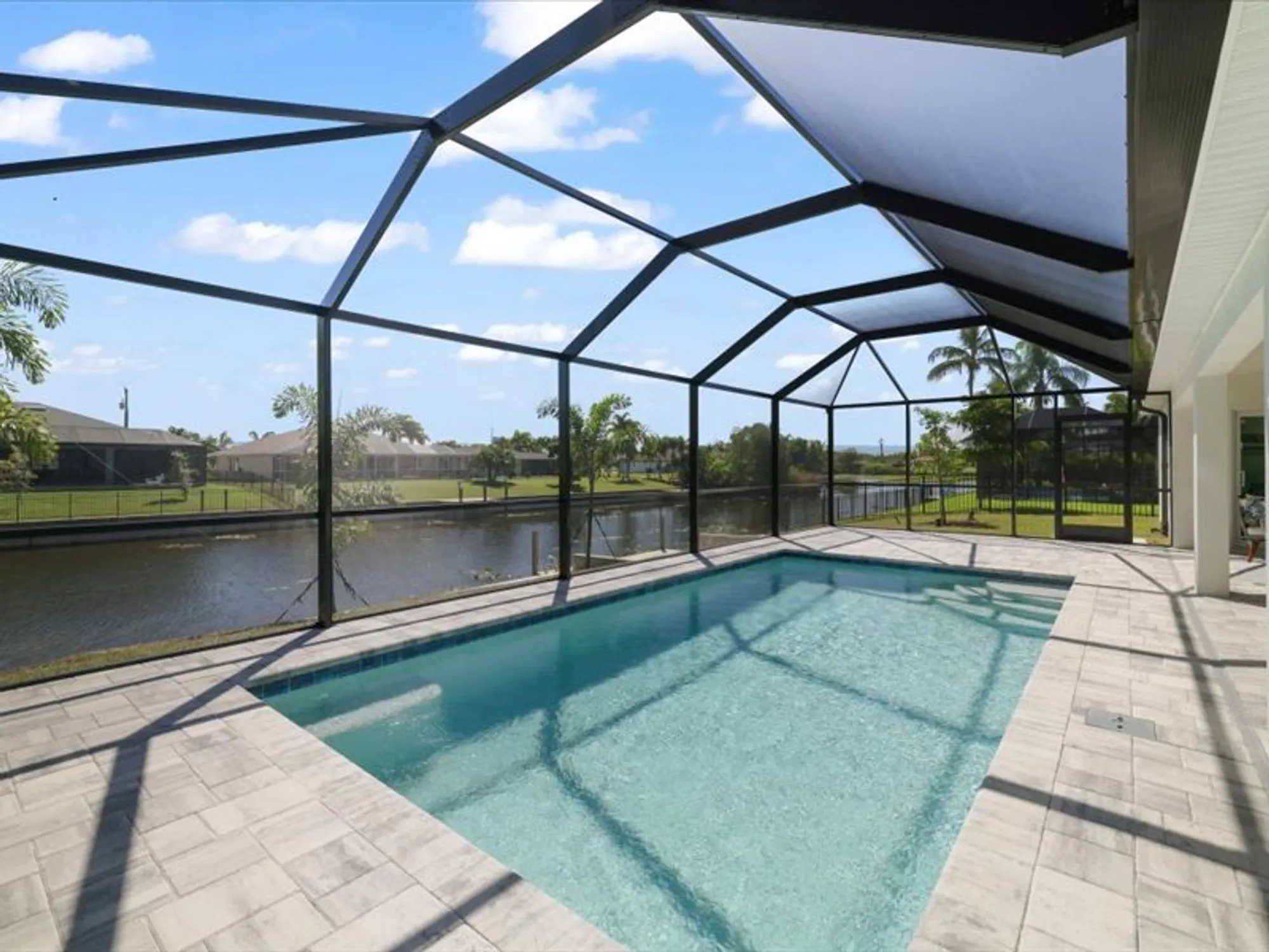Screened backyard pool overlooking canal and grassy yard