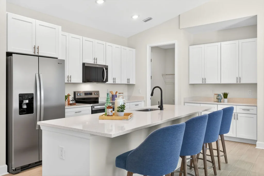 White kitchen with island sink, blue stools, stainless appliances