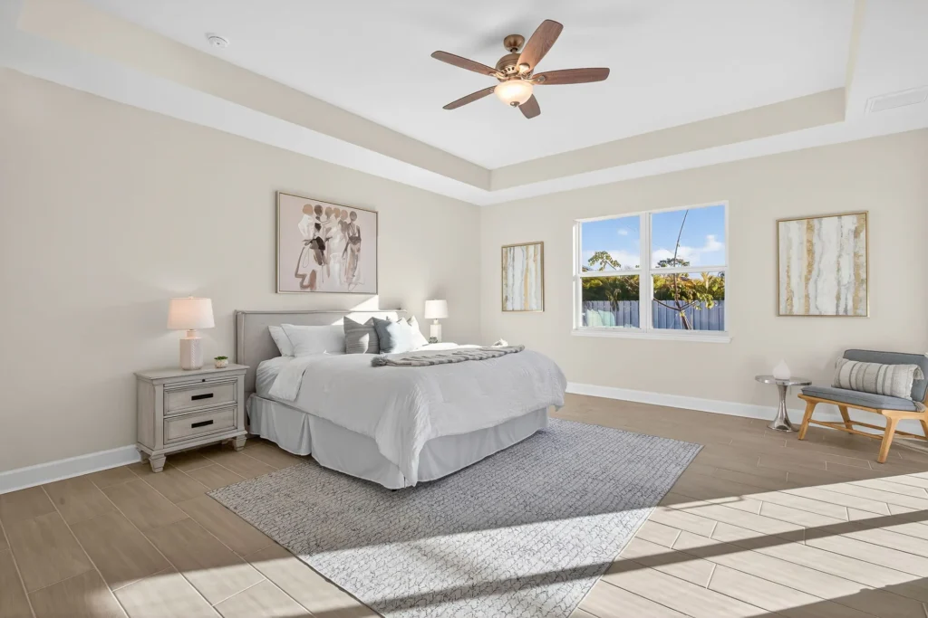 Bright bedroom with king bed, tray ceiling, and ceiling fan