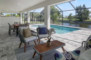 Covered patio seating beside screened pool overlooking canal