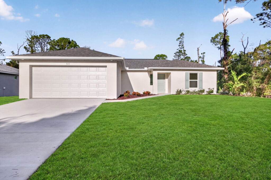 Single-story white home with two-car garage and green lawn