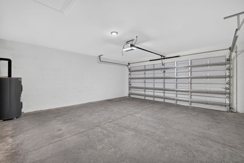 Empty garage with overhead door, opener, and concrete floor